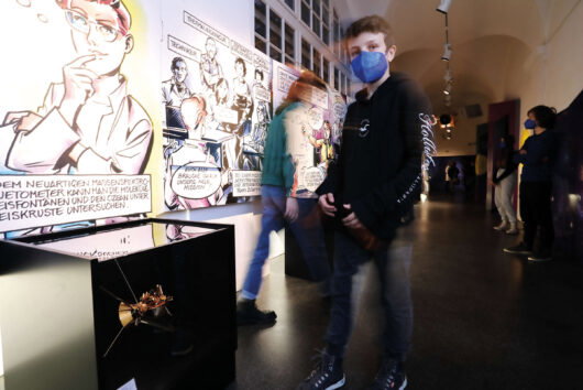 Kind in der Ausstellung "Mission Possible" im Grazer Joanneum vor riesigen Comic-Illustrationen von Chris Scheuer 
